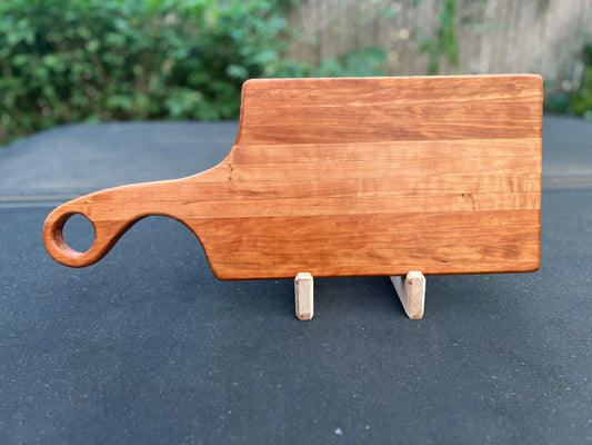 A cherry-colored charcuterie board featuring a variety of meats, cheeses, crackers, nuts, fruits, and garnishes arranged artistically on a wooden board.