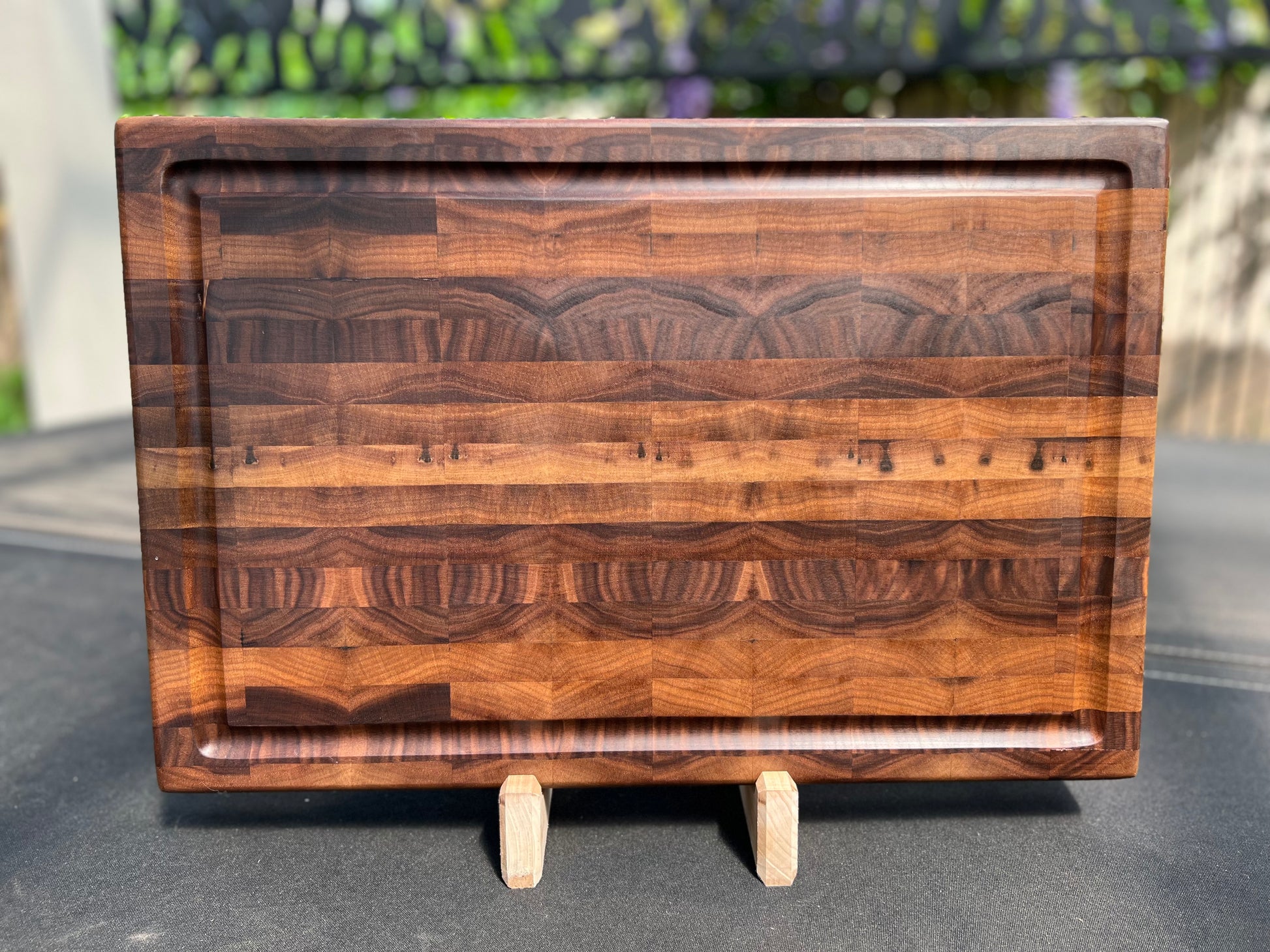 Large end grain walnut cutting board with a robust, textured surface that highlights the rich wood grain and provides durability for heavy use.