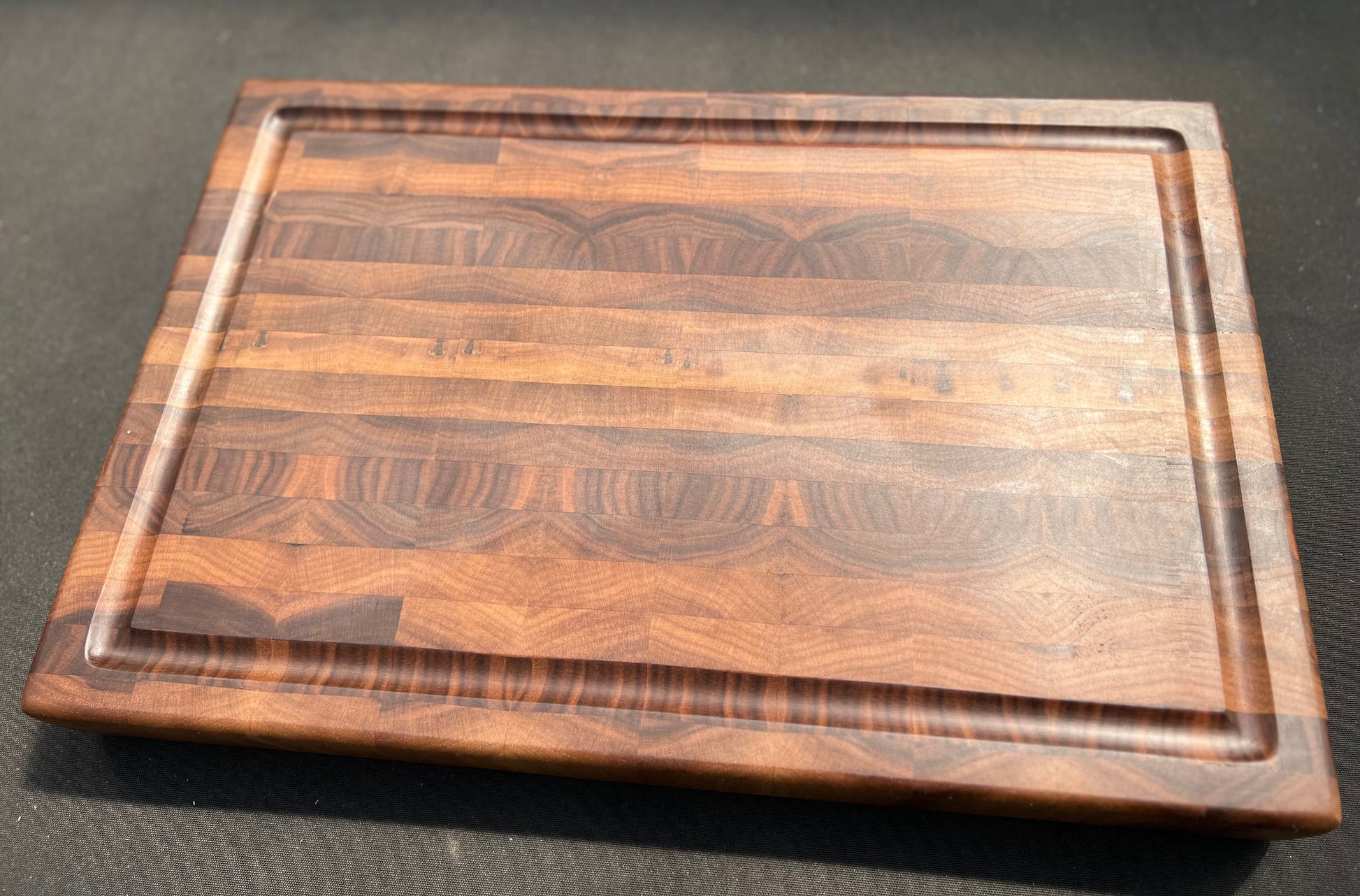 Large end grain walnut cutting board with a robust, textured surface that highlights the rich wood grain and provides durability for heavy use.